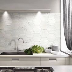 a white kitchen with an oven, sink and stove top in front of a window