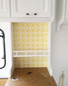 a kitchen with yellow wallpaper and white cupboards in the back ground, next to a wooden counter top