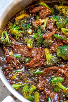 beef and broccoli stir fry in a pot with sesame seeds on the side