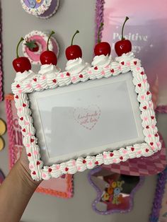 a person holding up a cake with cherries on it and a heart in the middle