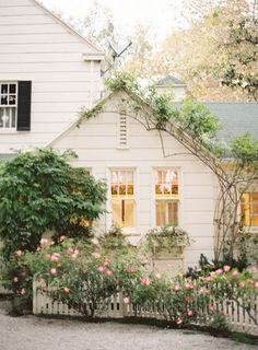 a white house with pink flowers in the front yard