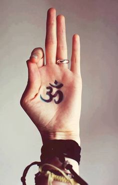 a person's hand with an om sign tattooed on it, holding up their palm