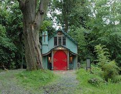 a red door is in front of a green building with a cross at the top