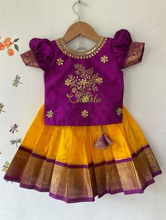 Traditional Kanchipuram silk skirt and raw silk top - yellow pavadai with maggam work purple top. BUYER'S PLEASE LEAVE YOUR CONTACT NUMBER. It's necessary for shipping. Leave message in the buyer note about the age of kid . Fabric and Work: Top: . Fabric used  is raw silk and is embellished with maggam work. The dress is lined with soft cotton fabric. The top has hook opening at back side of the dress. Skirt: Kanchipuram silk fabric with purple jacquard boarder and also lined with a cotton fabric to give comfort for your little one. The skirt has tie at waist line, If you need petticoat skirt we will customize it for you. Your little girl feels comfortable wearing this dress as it has a cotton lining for both top and skirt . It's a light weight soft Kanchipuram silk . If you need any custo Pattu Pavadai Kids Blouse Designs, Pattu Pavadai Designs, Pattu Pavadai, Kids Dress Collection, Kids Blouse Designs, Traditional Blouse Designs, Kids Lehenga, Kids Blouse, Kids Dress Patterns