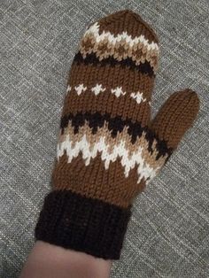 a person's hand wearing a brown and white knitted mitt on top of a couch