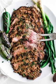 a piece of steak on a plate with green beans and asparagus