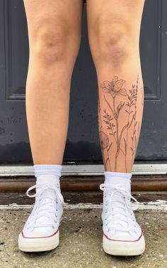 a woman's legs with tattoos on them and white tennis shoes in front of a door