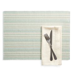 a fork and knife sitting on top of a white napkin next to a green striped place mat