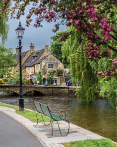 a bench sitting on the side of a river next to a lamp post and buildings