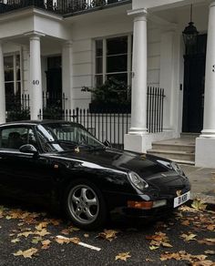 a black sports car parked in front of a white house with columns and railings