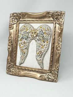 an ornate gold frame with beaded angel wings in the shape of a pair of shoes