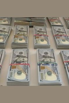 stacks of one hundred dollar bills tied with red and white ribbons on a table top