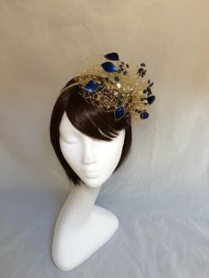 Delicate gold and navy veiled fascinator perfect for the guest who wants something fairly understated. This design is a beautiful selection of navy blue glass effect leaves clustered together amongst a fine layer of veiling and set onto a fine comfort base tiara band. As with all our designs, this piece can be made exact to the image or in any colour combination to match in with your outfit. If a specific colour is required customers can message over an image of their outfit and accessories, or Gold Headpieces For Royal Ascot Formal Occasion, Gold Mini Hats With Structured Crown For Evening, Gold Costume Hats For Evening At Royal Ascot, Gold Pinched Crown Hat For Evening, Gold Mini Hat For Royal Ascot Event, Gold Costume Hats With Structured Crown For Evening, Gold Headpiece For Evening At Royal Ascot, Gold Hats With Pinched Crown For Evening, Gold Mini Hat For Royal Ascot Wedding