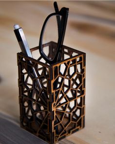 a pen and eyeglass holder made out of wood with laser cut design on it