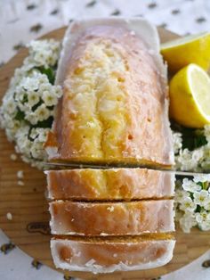 a loaf of lemon pound cake sitting on top of a wooden plate next to flowers