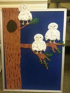 two owls sitting on a tree branch made out of construction paper and cutout leaves