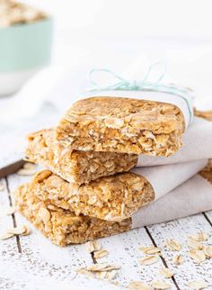 three oatmeal cookies stacked on top of each other next to a bowl of oats