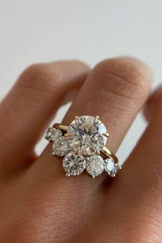 a woman's hand holding an engagement ring with three diamonds on top of it