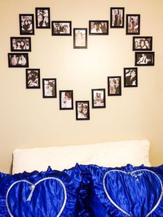 a heart shaped frame hanging on the wall above a bed with blue sheets and pillows