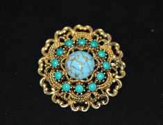 vintage Emmons gold and turquoise pin. This rare find is in very good condition. The gold threading is delicate and detailed to frame the center turquoise stone and surrounding turquoise accents.  Year: 1960-s Signed: No Condition: very good Brooch size: 4.5x4.5 cm Please note that all items are vintage, and not being new, will show varying degrees of signs of wear. If you have any questions please do not hesitate to contact me. Thank you for stopping by! Gold Cabochon Brooches For Jewelry Making, Vintage Gold Brooch With Cabochon, Vintage Gold Cabochon Brooch, Vintage Gold Brooches With Cabochon, Turquoise Brooch For Formal Occasions, Turquoise Cabochon Brooch For Gift, Turquoise Cabochon Brooch As A Gift, Handmade Vintage Turquoise Brooches, Handmade Turquoise Brooches For Collectible