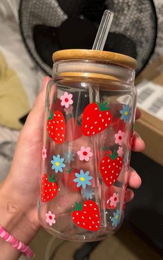 a person holding a glass with strawberries and flowers on it