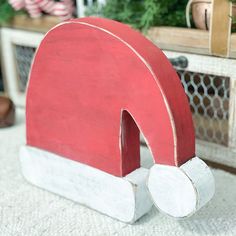 a red and white wooden object sitting on top of a rug next to a christmas tree