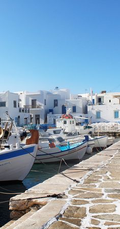 several boats are docked in the water next to some white buildings with blue shutters