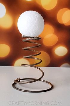 a white ball sitting on top of a metal wire sculpture with lights in the background