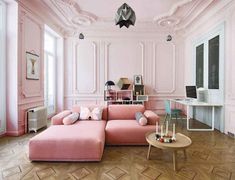 a living room with a pink couch and coffee table in front of a white wall