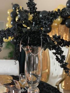 a vase filled with black flowers on top of a table next to candles and balloons