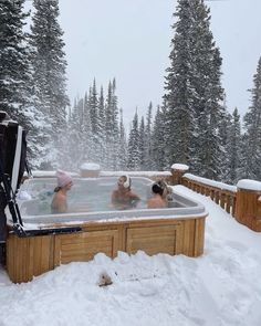 three people in a hot tub surrounded by snow