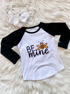 These Bee Mine Raglans are long sleeved black and shite shirts with "Be Mine" and a cute little bumble bee on the front. Perfect for Valentine's Day! Adult shirt Only. Children's sizes are currently out of stock. Includes: Child or adult raglan shirt only Fit: True to size Cute Black Crew Neck Shirt, Spring Long Sleeve T-shirt With Character Print, Cute Black Tops With Cartoon Print, Cute Black Tops With Letter Print, Cute Black Top With Cartoon Print, Playful Black Cotton Shirt, Cute Black Shirt For Spring, Black Long Sleeve Top With Character Print, Long Sleeve Cotton Shirt With Character Print