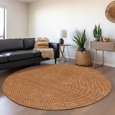 a living room with black leather couches and a round rug