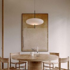 a dining table with four chairs and a painting on the wall in an empty room