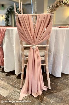 the back of a chair covered in pink chiffon draped over it's seat