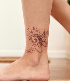 a small tattoo on the ankle of a woman's leg with a fairy sitting on it