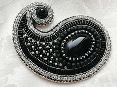 a black and white brooch with an oval shaped design on it's side