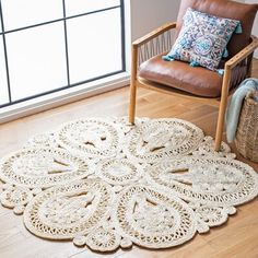 a chair sitting next to a rug on top of a wooden floor in front of a window