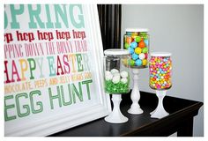 some candy jars are sitting on a table next to a framed sign that says spring