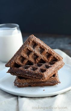 three waffles stacked on top of each other on a plate next to a glass of milk