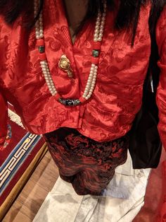 a woman wearing a red shirt and pearls necklace