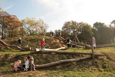 several children are sitting on the ground and playing in an obstacle course made out of logs