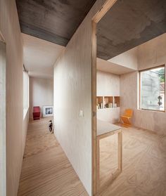 an empty room with wooden walls and flooring is seen from the hallway to the living area