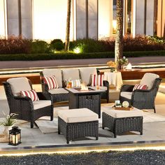 an outdoor seating area is lit up at night with red and white pillows on it