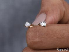 a woman's hand holding a ring with two small diamonds on the middle of it