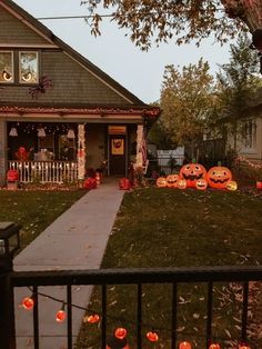 a house decorated for halloween with pumpkins on the lawn