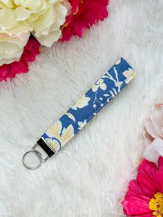 a blue and white flowered key fobring on a furry surface with flowers in the background