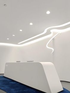 a modern white room with blue carpet and lights on the ceiling is lit by recessed lighting