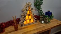 a wooden christmas tree with lit candles in it on a table next to other decorations