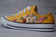 a pair of yellow shoes with flowers painted on them